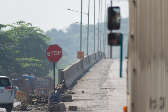 A stop sign on a damaged road near ongoing construction along Samriddhi Mahamarg connecting Bhiwandi and Padgha, showing traffic slowdown, infrastructure work and highway development.