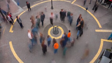 Vista aérea de personas moviéndose en círculo en una plaza urbana con efecto de desenfoque por movimiento.