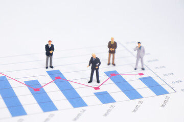 Fototapeta premium Miniature figures businessman standing on a graph chart financial with copy space using as background. businessman analyze achievement data