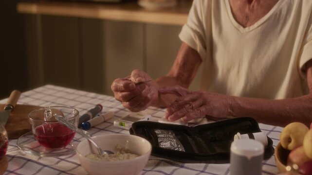 Medium close-up of anonymous elderly woman with autoimmune diabetes measuring blood sugar with fingerstick test after eating oatmeal porridge for breakfast, inserting strip into glucose meter