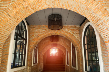 Arch  or curve  of entrance hall building with lamps on ceiling to decorated on the brick wall. Corridor connecting walkway tunnel with lighting in the end.