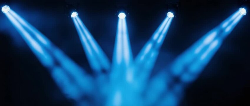 Dynamic blue spotlights illuminate stage with atmospheric haze perfect for concerts and events