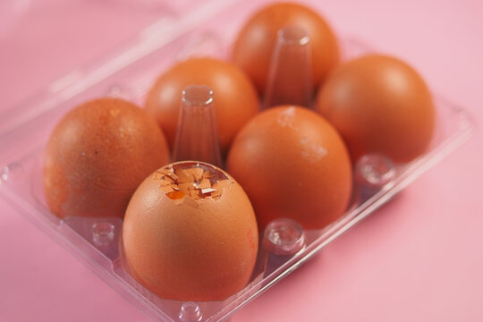 Fresh brown eggs in a carton on a pink background