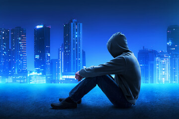 Man in hoodie sitting on the roof top at beautiful blue night city sky