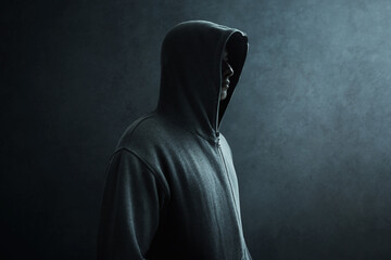 Hacker in hoodie on dark background