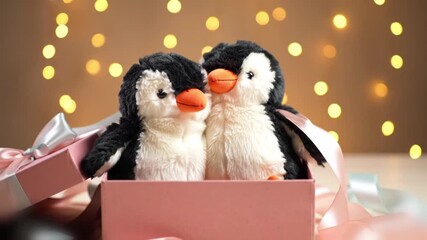 enchanting gift box reveal of two plush penguins hugging inside a pastel ribbon nest with twinkling fairy lights above - Powered by Adobe