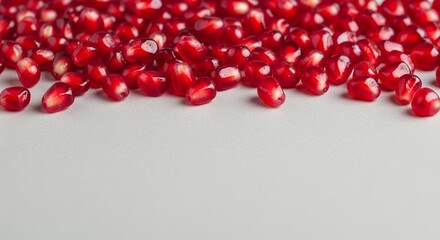 A close up shot of scattered pomegranate seeds on a white surface with a shallow depth of field effect
