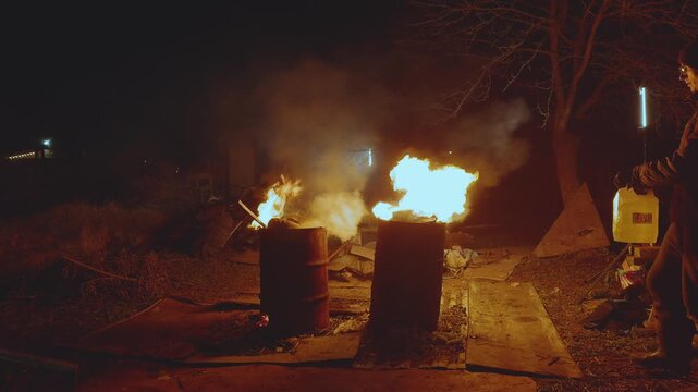 Burning trash in barrels, a man burns trash in barrels