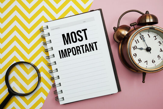 Most Important text written on notepad with alarm clock and magnifying glass