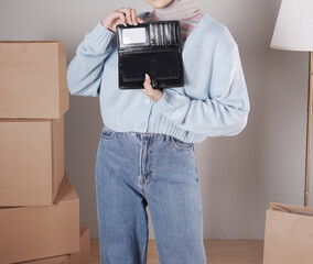 Young woman's body in a knitted sweater and jeans and her hand showing an elegant shiny black leather purse
