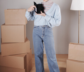 Young woman's body in a knitted sweater and jeans and her hand showing an elegant shiny black leather purse