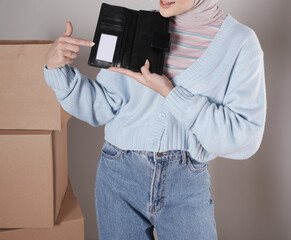 Young woman's body in a knitted sweater and jeans and her hand showing an elegant shiny black leather purse