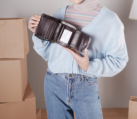 The body of a young woman in a knitted sweater and jeans and her hand shows an elegant shiny dark brown leather purse.