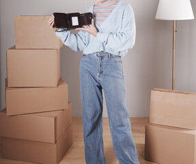 The body of a young woman in a knitted sweater and jeans and her hand shows an elegant shiny dark brown leather purse.