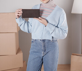 Young woman's body in a knitted sweater and jeans and her hand showing an elegant matte brown leather purse