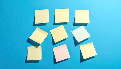 Arrangement of Yellow and Pink Sticky Notes on a Vivid Blue Surface under Strong Lighting with Sharp Shadows
