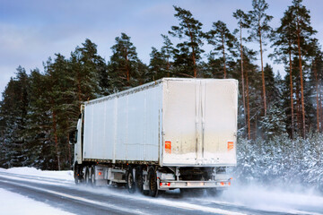 Semi Truck Transports Goods along Icy and Snowy Highway. Challenging Driving Conditions. 
