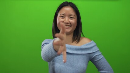 Woman smiling and extending hand for handshake against isolated green background wall wearing blue top symbolizing friendly introduction opportunity.