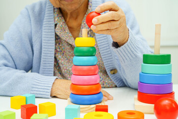 Asian elderly woman playing enhancing skill board game.