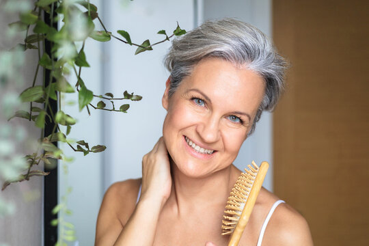 Portrait of a beautiful, smiling middle-aged European woman with gray hair in the bathroom