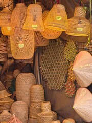 Handmade woven lampshades and hats on display in a market stall