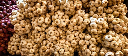 Fresh garlic bulbs and red onions at a farmers market stall