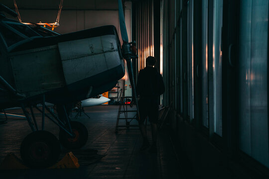 person inspecting airplane in hangar evening