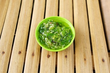 Top view of fresh green chili sambal served in a bowl, showcasing spicy Indonesian condiment texture and vibrant culinary presentation.
