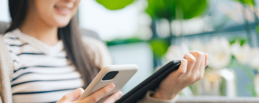 Woman using smartphone and tablet, working or relaxing indoors