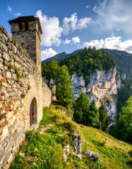 Ancient stone fortress wall with tower, overlooking a mountain