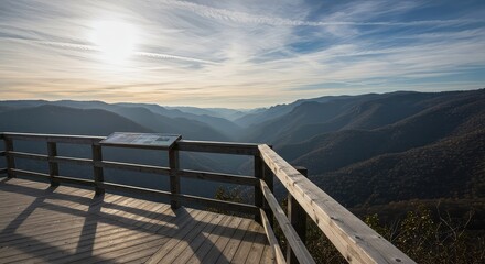 Fototapeta premium A wooden observation platform and protective railing offering a panoramic vista of the deep valley and distant mountain range ,valley ,overlook ,elevation