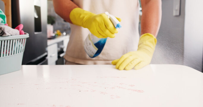 Cleaning, hands and spray in kitchen with disinfectant, housework or sanitation of countertop. Space, chores or person in house with detergent, bacteria and germ removal in liquid container.