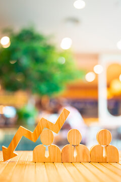 Wooden arrow pointing down over businessperson icons symbolizing workforce reduction, employee layoff, HR crisis, business downturn, or poor corporate performance in economic context.