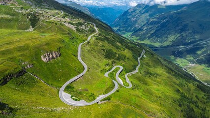 A stunning aerial view showcases a winding mountain road traversing a vibrant green alpine landscape in Austria, ideal for travel projects and tourism promotions.
