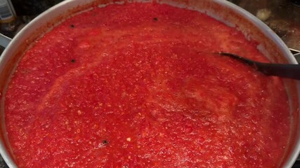 An overhead view of simmering homemade tomato sauce and a woman's hand stirring pasta, pizza, or mea.t sauce  - Powered by Adobe