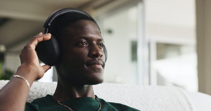 House, headphones and black man on couch, thinking and listening to music, sound and playlist album. Calm, relax and person on sofa, audio tech and radio with daydreaming and streaming song in lounge