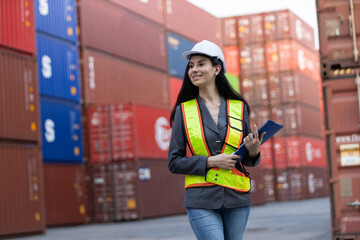 Portrait of confident female logistics engineer in safety uniform holding clipboard at container yard, symbolizing leadership, accuracy, cargo management in shipping industry.
