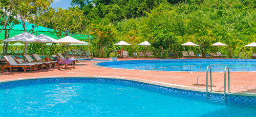 swimming pool at a tropical luxury resort in summer. Tourism and recreation. Landscape panorama with a pool and sun loungers and umbrellas