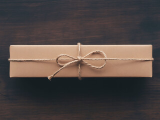 Simple Kraft Paper Gift Box Tied with Twine on Dark Wooden Background