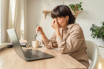 Mature woman experiencing eye strain from laptop work