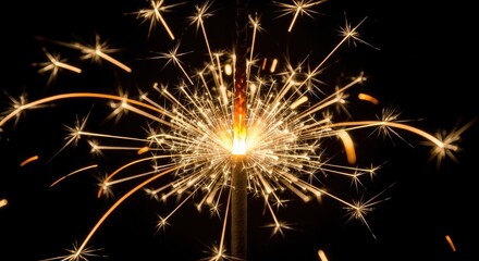 Fototapeta premium Close up of a sparkler emitting bright sparks against a black backdrop