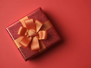 Sparkling red gift box tied with shiny golden ribbon bow from above