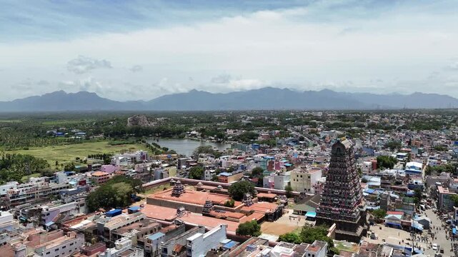 Vibrant aerial video of Tenkasi, Tamil Nadu, showcasing the historic Kasi Viswanathar Temple towering temple gopuram, calm water body, lush greenery, and majestic Western Ghats beyond.