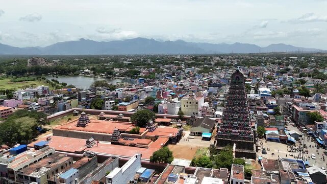 Scenic aerial video of the famous Tenkasi Kasi Viswanathar Temple surrounded by dense urban streets, ancient architecture, and natural landscapes in Tamil Nadu.