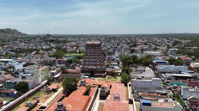 Aerial close-up of the Kasi Viswanathar Temple in Tenkasi, Tamil Nadu, with its towering gopuram surrounded by colorful town buildings and hills in the distance under a bright sky.