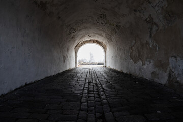 Fototapeta premium An empty ancient dark tunnel with bright glowing end, abstract photo background