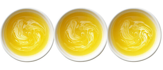 Three bowls of vibrant yellow liquid with swirling patterns, arranged in a row against a plain background, ideal for culinary presentations or food-related content