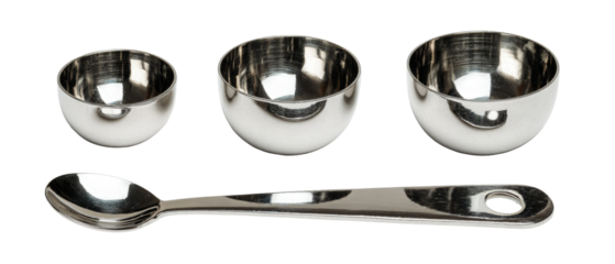 A set of three shiny stainless steel measuring cups alongside a stainless steel spoon, arranged neatly on a white background, ideal for culinary use and kitchen organization