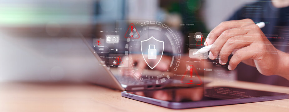 Cybersecurity and data protection concept with digital shield icon, hacker warning alerts, and person using laptop computer for secure network system monitoring.
