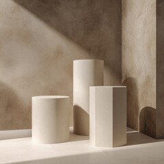 Three off-white geometric display stands?two cylinders and a hexagon?rest on a light-colored surface, bathed in sunlight against a textured, earthy-toned wall with arched recesses